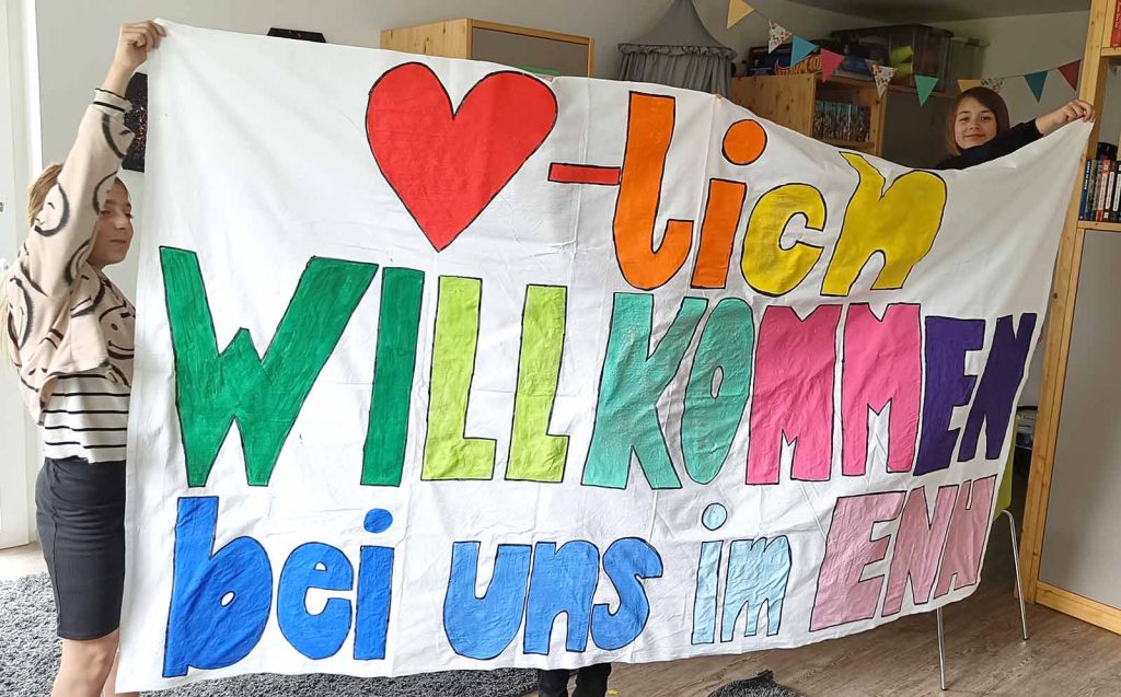 Kinder halten ein Willkommenstransparent hoch