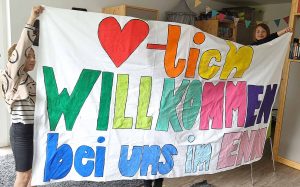 Kinder halten ein Willkommenstransparent hoch