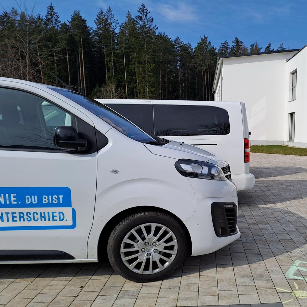 Ein weißes Auto mit der Aufschrift "Du bist der Unterschied" steht auf einem Hof.