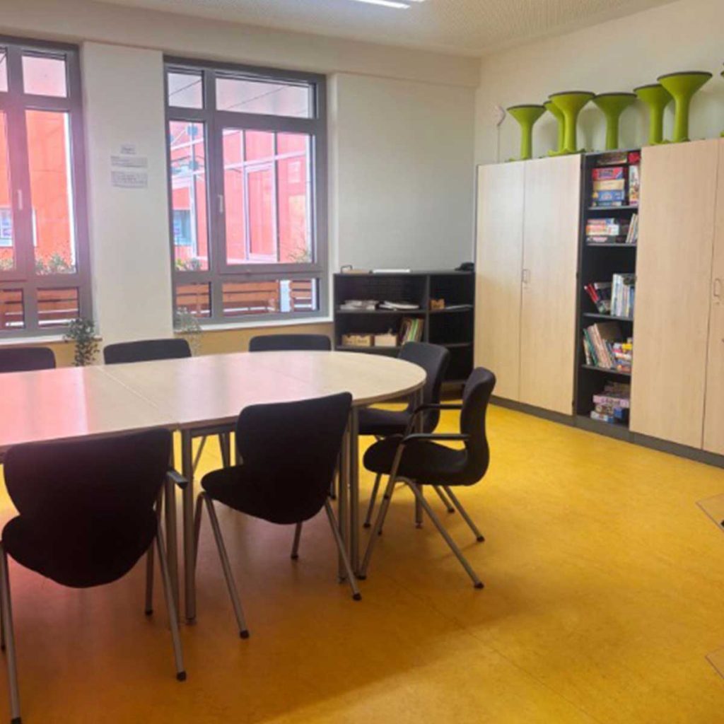 Ein Besprechungsraum mit einem Tisch und Stühlen, die dabei stehen.